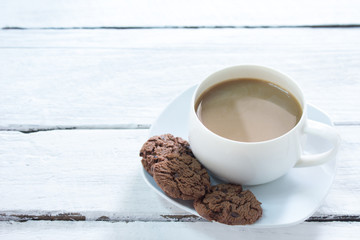 White coffee mug on white painted wood floor,.With black cookie dessert,.Morning meal