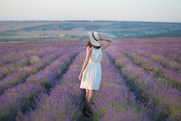 Young beautiful lady with lovely face walking on the lavender field on a weekend day in wonderful...