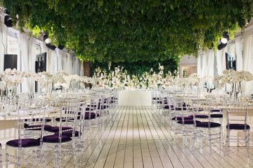 Tables decorated with orchids and violet chairs under green ceiling