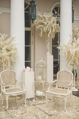 White chairs and vases with flowers stand between white pillars outside