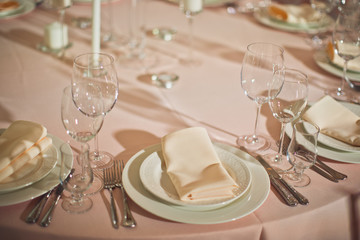 Beige serviette lies on white plate on pink dinner table