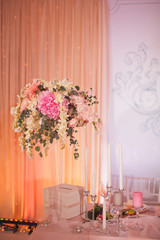 Tall vase with beautiful bouquet stands on pink dinner table