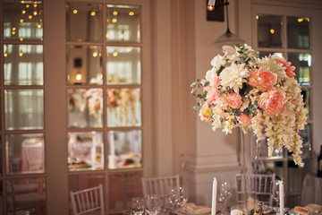 Tall vase with beautiful bouquet stands on pink dinner table