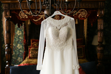 White wedding dress with laces hangs from steel chandelier
