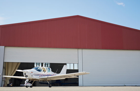 Wide angle graphic image of small jet plane standing in hangar of airport field