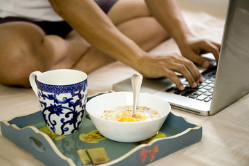 Selected focus blow of cornflakes and coffee mug breakfast on a tray with man using