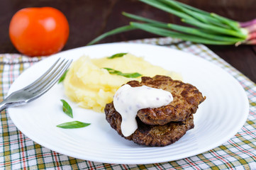 Juicy liver cutlet with sauce and mashed potatoes on a white plate.