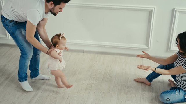 Dad teaches his little daughter to walk. Baby's first steps