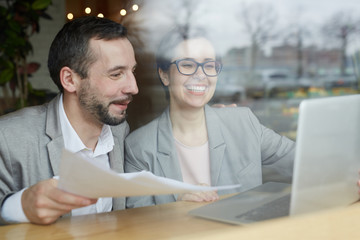 Joyful colleagues reading business data in the internet