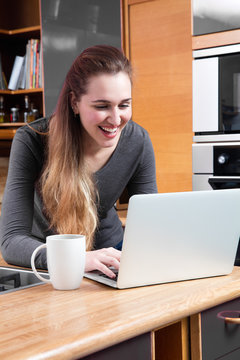 laughing young woman with computer to telecommute or buy online