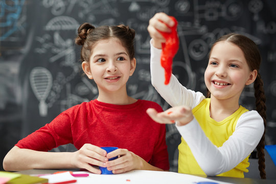 Playful girl having fun with red slime while her friend looking at this