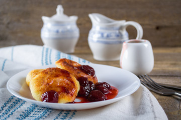 Country or rustic style breakfast. Cottage cheese pancakes with strawberry jam on old wooden table.