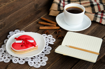 Fototapeta na wymiar Cozy rest. Coffee mug, gingerbread in the shape of heart, notepad with pencil, spices