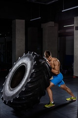 Fototapeta na wymiar Crossfit training - man flipping tire in gym