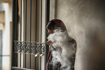 Vape man. Photo of a handsome young white guy in the hood vaping and letting off steam from an...