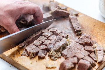 The cook cuts boiled beef meat