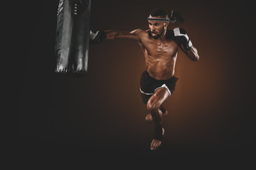 Naklejka premium angry muay thai fighter practicing punch on punching bag, action sport concept