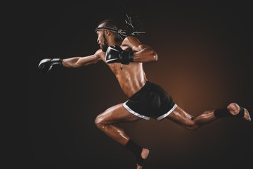 Fototapeta na wymiar side view of muay thai fighter in boxing gloves practicing punch, action sport concept