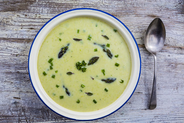 Delicious creamy asparagus soup on a wooden background.