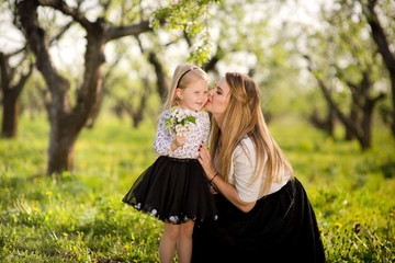 Obraz premium Little daughter gives her mother flowers for the holiday, a walk in the spring garden