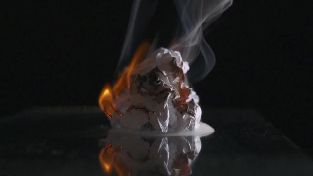 Fire, the process of burning paper, smoke, slow motion, black background. Close-up.
