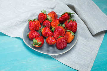 fresh red strawberries on ceramic gray plate on wooden tabletop