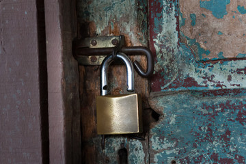 Vintage (retro) metal lock on a wooden door. Classic hanging lock. Attrition, old paint and dirt. Soft focus.