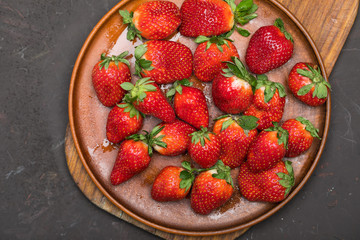 fresh red strawberries in ceramic plate on wooden cutting board, berries top view concept