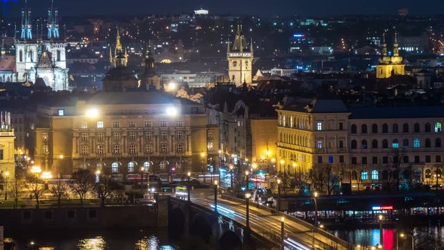 Wonderful view on the Charles bridge in Prague with old and arty sculptures, lit lanterns, moving back and forth people in the evening twilights, in  spring, taken as a timelapse and zoom out shot