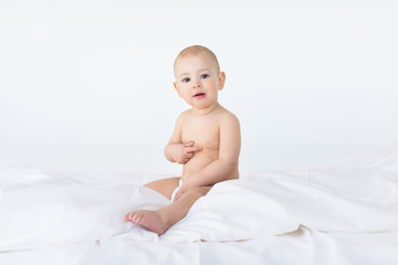 adorable baby boy sitting on bed  isolated on white, 1 year old baby concept