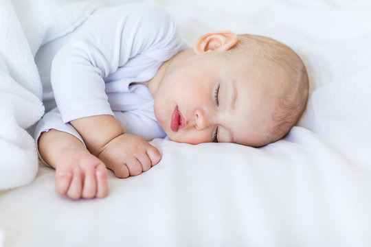 Close-up portrait of adorable baby boy sleeping in bed, 1 year old baby concept