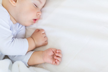 Close-up portrait of adorable baby boy sleeping in bed, 1 year old baby concept