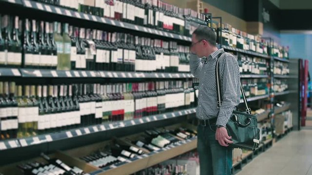 Handsome man choose the wine in the supermarket