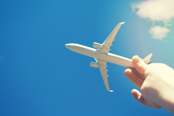 Fototapeta na wymiar dreams of journey - hand with small airplane model against blue sky