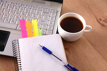 Office table with blank notepad and laptop 