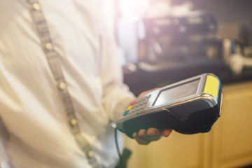 Close up of waiter holding the payment terminal in coffee shop.