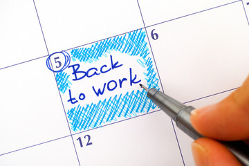 Woman hand with blue pen writing reminder Back to Work in calendar