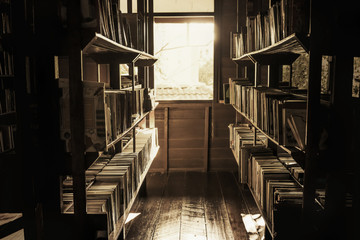 In the old library, the books on the shelves were cluttered, the light shining out of the window in a lonely atmosphere, vintage style.
