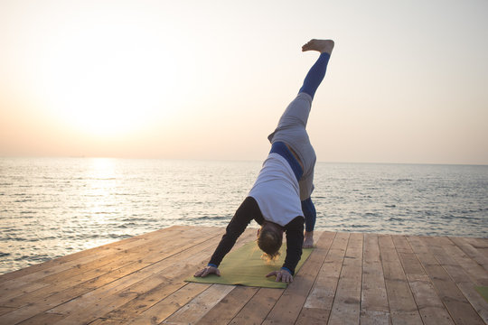 Young man doing yoga in the beach. Morning sea background. 
