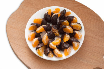 Slices of tangerine in chocolate on wooden cutting board