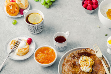 Morning atmosphere. Healthy breakfast with porridge, oatmeal, pancakes, lots of berries and snacks on blue rustic background. Text space at the center.