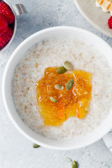 Morning oatmeal with homemade orange confiture and raspberry. Closeup