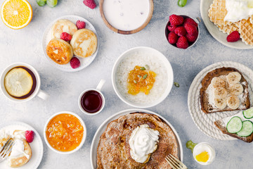 Morning atmosphere. Healthy breakfast with porridge, oatmeal, pancakes, lots of berries and snacks on blue rustic background.