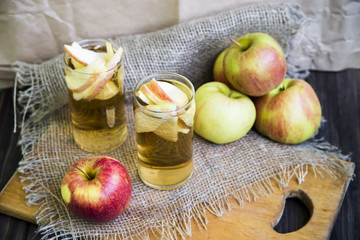 Apple cider with slices of apples in transparent glasses on a wooden board