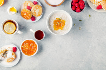 Morning atmosphere. Healthy breakfast with porridge, oatmeal, pancakes, lots of berries and snacks on blue rustic background. Copy space