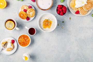 Morning atmosphere. Healthy breakfast with porridge, oatmeal, pancakes, lots of berries and snacks on blue rustic background. Copy space