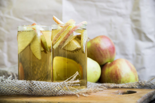 Apple cider with slices of apples in transparent glasses on a wooden board