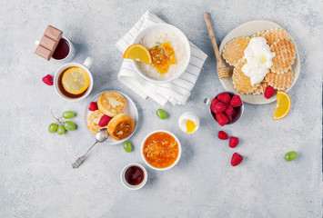 Morning atmosphere. Healthy breakfast with porridge, oatmeal, pancakes, lots of berries and snacks on blue rustic background.