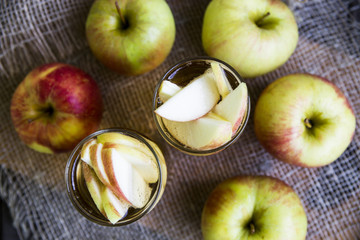 Apple cider with slices of apples in transparent glasses on a wooden board