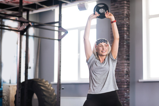 Delighted active woman lifting weights